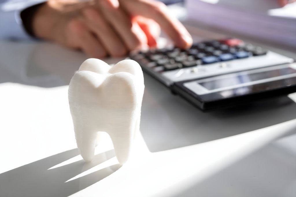 tooth with dentist using calculator in background